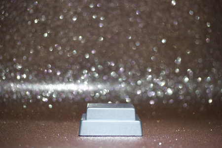 A small rectangular object is placed on a shiny surface while light sparkles softly surround it. The setting is simple with a muted color background creating a subtle focus.の写真素材