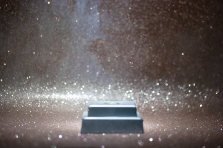 A close view shows a small object sitting on a surface that reflects light. Tiny particles float in the air, creating a sparkling effect that draws attention.の写真素材