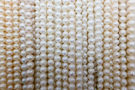 Several strands of white pearls are arranged side by side. Each strand shows different shapes and...