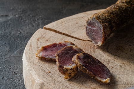 Slices of dried meat on wooden cut on dark rustic background. Snack and appetizer conceptの写真素材