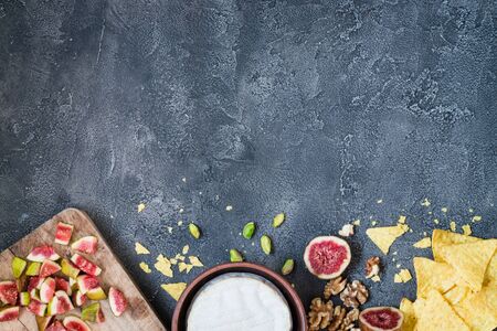 Ingredients layout for baking soft cheese brie with figs, walnuts, pistachios and honey. Snack concept with chips. Top view on dark background with copy spaceの写真素材