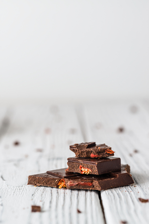 Raw handmade chocolate with goji on white wooden background. Healthy sweets concept. Copy spaceの写真素材