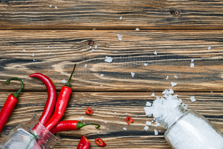 Red chili peppers and sea salt in glass jar on wooden table. Top view. Copy spaceの写真素材