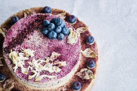 Raw blueberry cheesecake, homemade with decoration of dried flowers and fresh berries. Healthy handmade dessert. White backgroundの写真素材