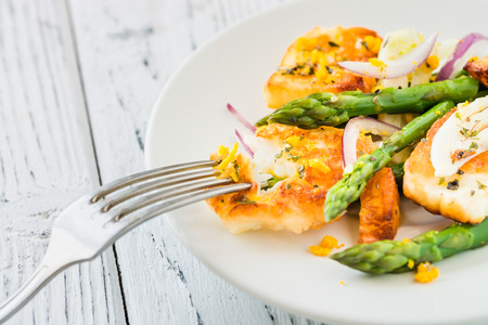 Salad with fried halloumi, asparagus and orange zest. Close up. White wooden backgroundの写真素材