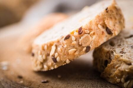 Fresh, healthy whole grain rye baguette and slices on cloth and rustic wooden board, close up....