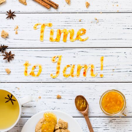 Food typography Time to Jam on white wooden rustic background. Orange jam lettering with tea, cookies, cinnamon sticks and anise. Holiday dessert conceptの写真素材