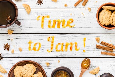 Food typography Time to Jam on white wooden rustic background. Orange jam lettering with cookies, tea, cinnamon sticks and anise. Holiday dessert conceptの写真素材