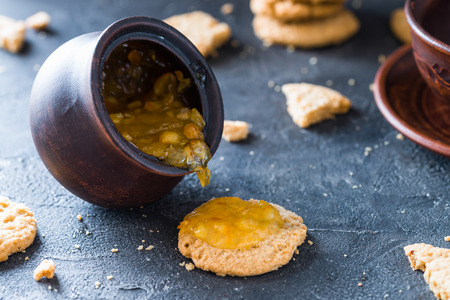 Clay pot with orange jam, over a cookie on dark rustic background. Dessert conceptの写真素材