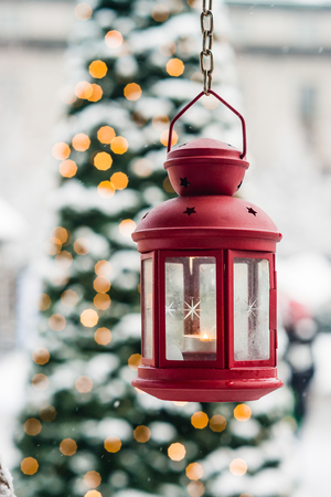 Christmas lantern hanging, with pine and lights in the background