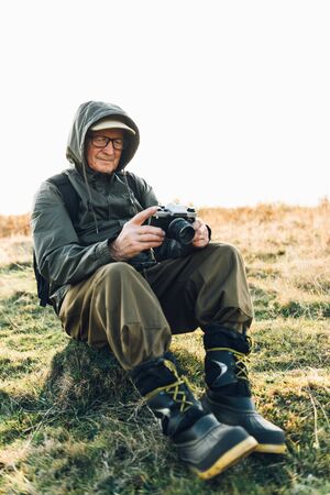 Old man taking photo in misty woods.の写真素材