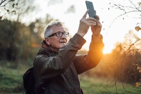 Old man doing selfie in sunset.