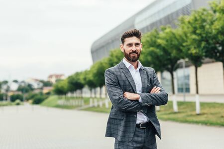 Portrait of sexy handsome fashion businessman model dressed in elegant blue suit posing on street backgroundの写真素材
