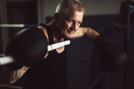 Elderly boxer thinks about tactics before a fight in the ring.の写真素材