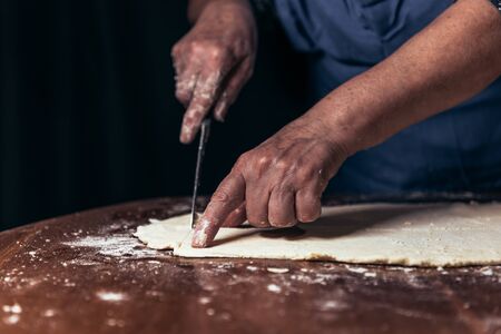 A woman is preparing dough at domestic kitchen