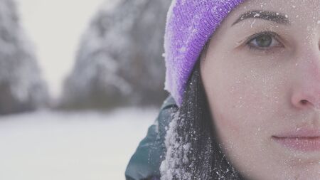 lonely girl in the woods smiling looking at the camera, covered with snow