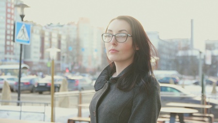 attractive girl with glasses and coat in the background of the cityscape