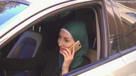 beautiful muslim woman driving a car talking on the phone smilingの写真素材