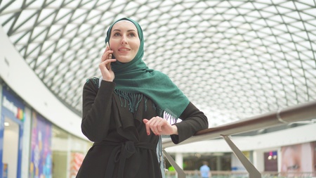 Muslim girl in hijab talking on the phone in the modern business centerの写真素材
