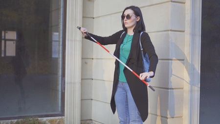 portrait of a blind girl in glasses with a cane