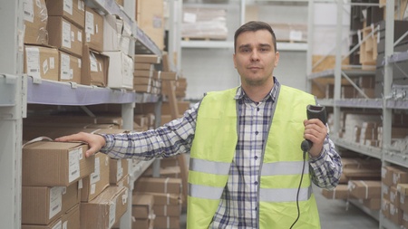 Portrait man store worker using bar code scanner scanning labels on boxesの写真素材