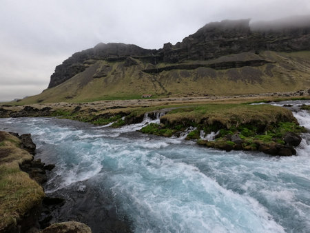 Icelandic landscape with river and mountains in cloudy weather. Iceland.の写真素材