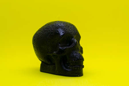 A black wax skull on a yellow background.の写真素材