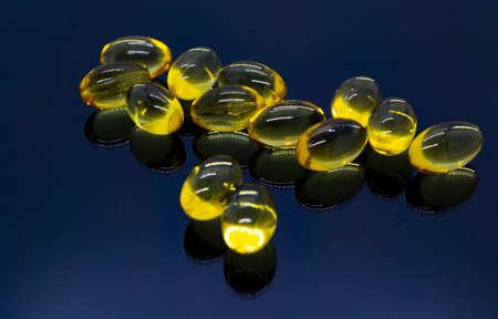 Omega 3, yellow transparent fish oil capsules with a reflection at the bottom.の写真素材
