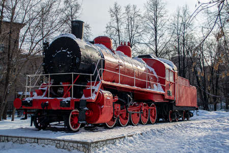 A red steam locomotive is standing on the platform.