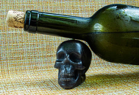 A bottle of wine on a black skull made of wax.の写真素材