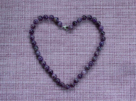 Purple beads laid out in the form of a heart.の写真素材