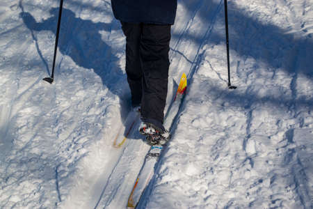 A child on skis with sticks, walking on a rolled ski track.