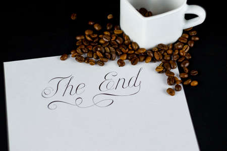 A white heart-shaped mug with coffee beans and the inscription end, on a blurry background.の写真素材