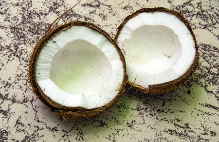 Two split coconut halves on a beautiful decorative background.