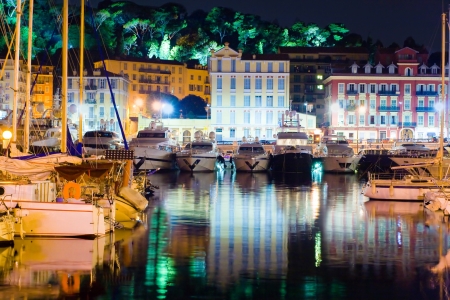 Image of yacht parked with a beautiful reflection of the city at night. In the background are seen the lights of the park in Nice, Franceの写真素材