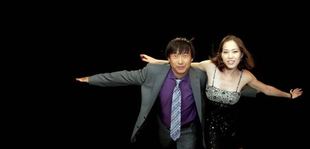 Happy asian couple flying together isolated on the black backgroundの写真素材