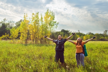 Happy young couple hiking with backpack at autumn in forestの写真素材