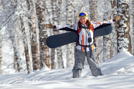 Portrait image of young snowboarder women is going for freeride to uphill through forestの写真素材