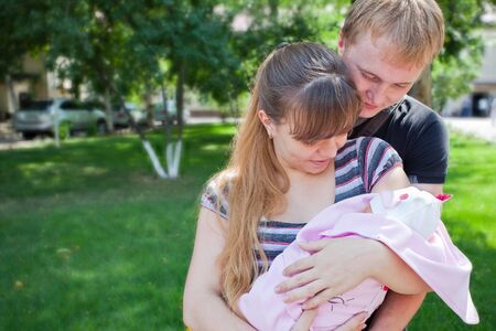 Image of young parents holding the hands of his first child - a girl on a sunny summer day. Almaty.の写真素材