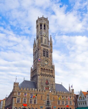 Vertical panorama of the main tower of old part in Bruges. Front view bottom-up on the background of the cloudy sky. Belgiumのeditorial素材