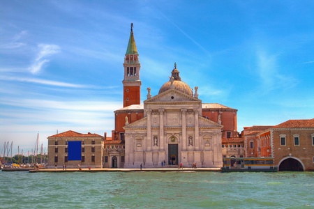 Picture of boat on the canal in Venice, on the background of one of the old part of town with colorful houses and a church.のeditorial素材
