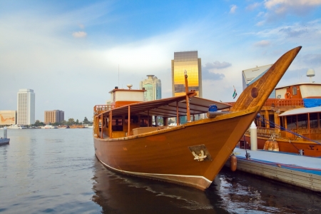 Picture of moored boats in the Arabian style against the backdrop of skyscrapers in Dubai with the reflections of the sunset の写真素材