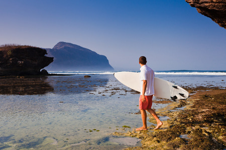 Surfer with surfboard on a coastline of Sumbawa, Indonesiaの写真素材