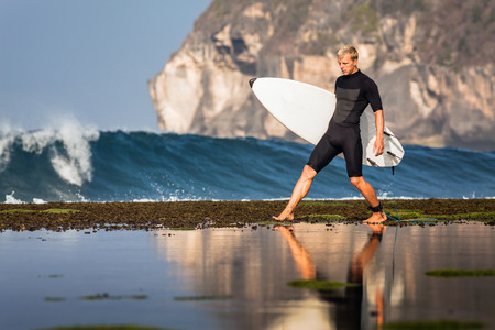 Surfer with surfboard on a coastline of Sumbawa, Indonesiaの写真素材