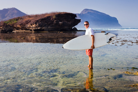 Surfer with surfboard on a coastline of Sumbawa, Indonesiaの写真素材