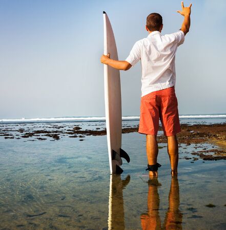 Surfer with surfboard on a coastline of Sumbawa, Indonesiaの写真素材