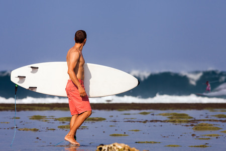 Surfer with surfboard on a coastline of Sumbawa, Indonesiaの写真素材