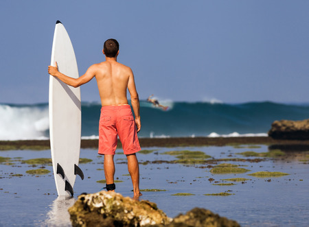 Surfer with surfboard on a coastline of Sumbawa, Indonesiaの写真素材