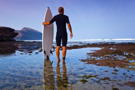 Surfer with surfboard on a coastline of Sumbawa, Indonesiaの写真素材