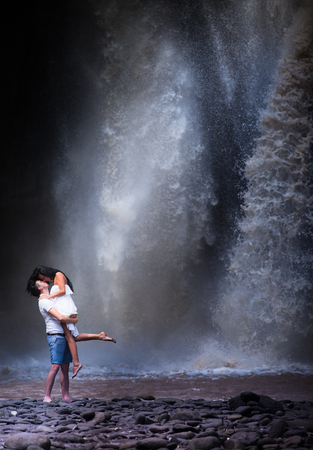 kissing couple travel near the big waterfallの写真素材